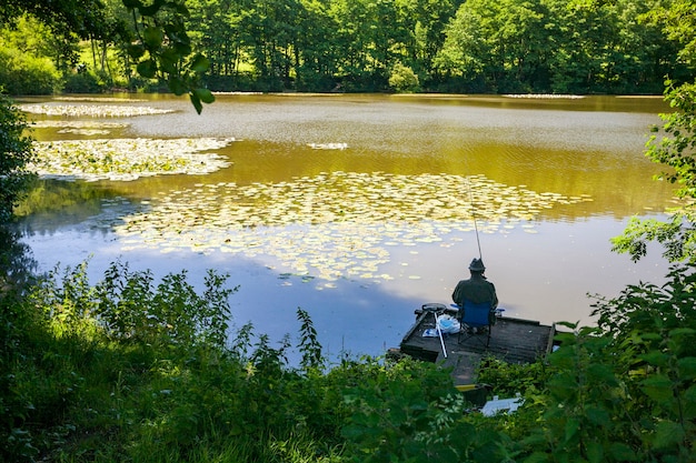 Vista traseira de uma pessoa pescando em um lago em Wiltshire, Reino Unido, no início da manhã