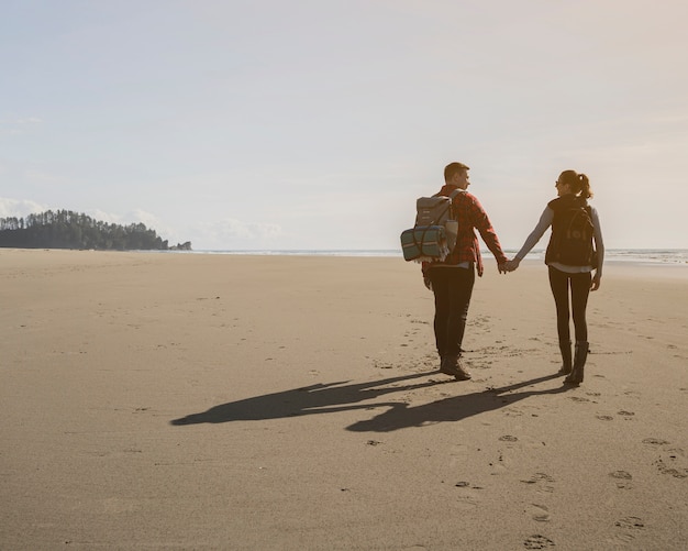 Vista traseira do casal de mãos dadas na praia