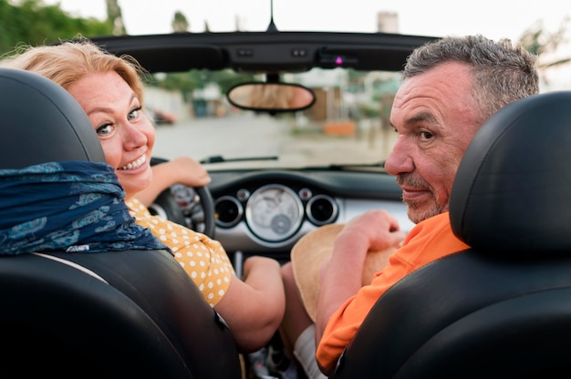 Vista traseira do casal de turistas mais velho de férias em carro