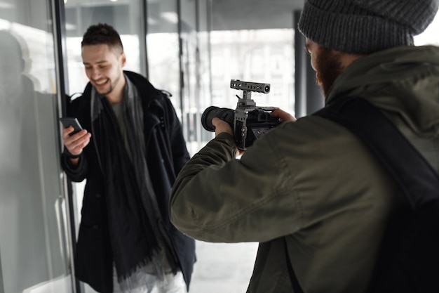 Vista traseira do fotógrafo tiro modelo masculino bonito lá fora.