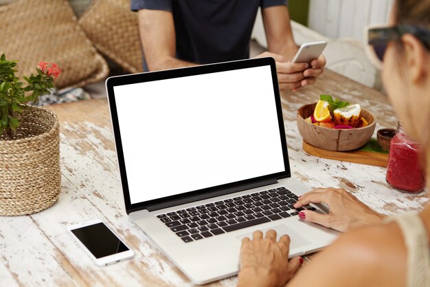 Vista traseira do freelancer feminino digitando no pc laptop enquanto trabalhava remotamente. Mulher elegante em tons usando computador notebook