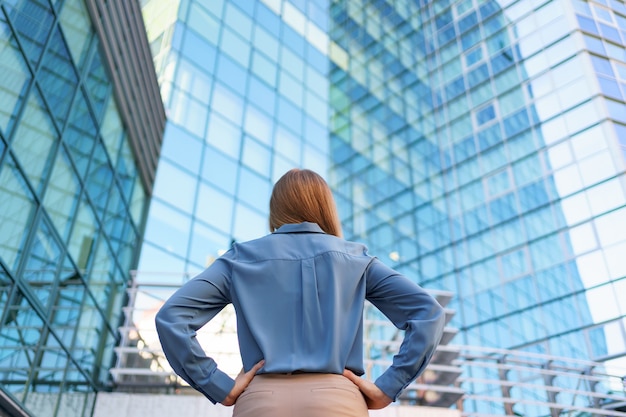 Vista traseira do gerente bem-sucedido, olhando para o edifício comercial da cidade moderna.