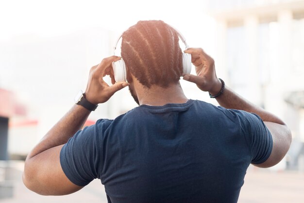 Vista traseira do homem afro-americano ouvindo música com fones de ouvido