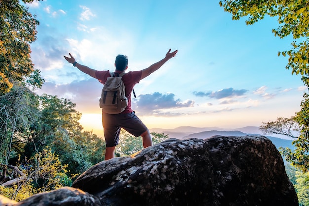 Foto grátis vista traseira do jovem caminhante asiático em pé e levantando as mãos com feliz no pico do espaço de cópia da montanha rochosa