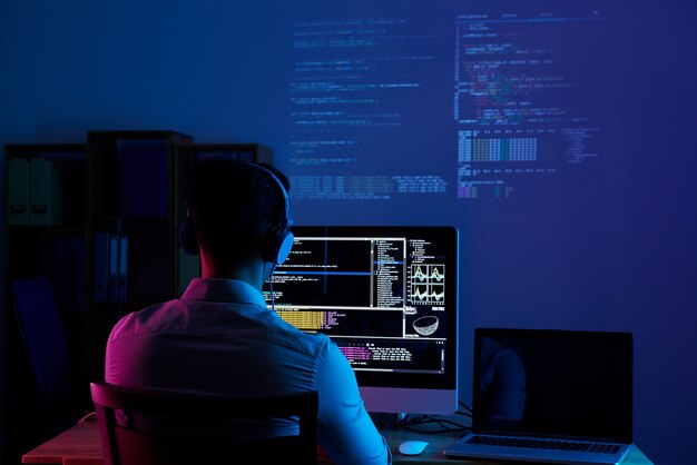 Vista traseira do programador trabalhando a noite toda