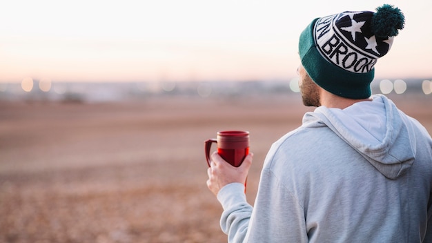 Vista traseira homem com thermos desfrutando de paisagem