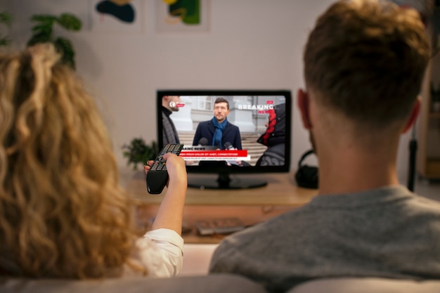 Vista traseira homem e mulher assistindo tv