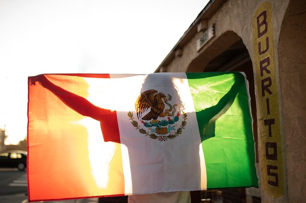 Vista traseira homem segurando a bandeira mexicana