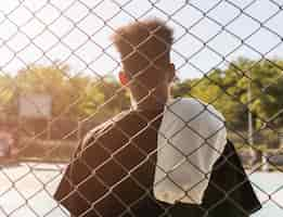 Foto grátis vista traseira jovem em um campo de basquete