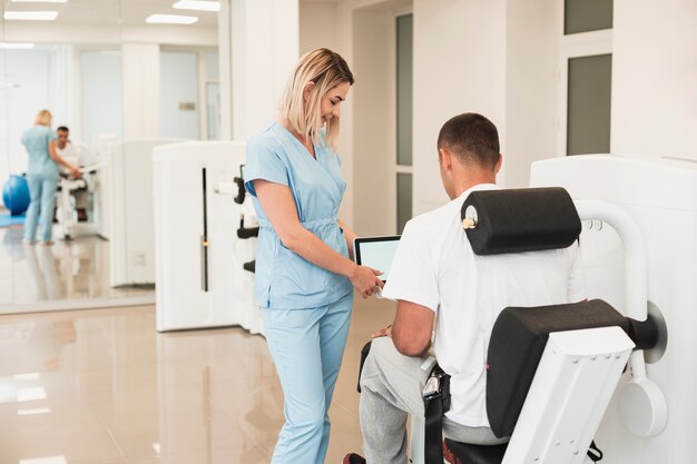 Vista traseira médico ajudando paciente com um médico exercitado