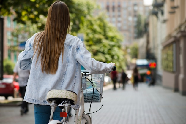 Vista traseira, mulher caminhando, perto, bicicleta