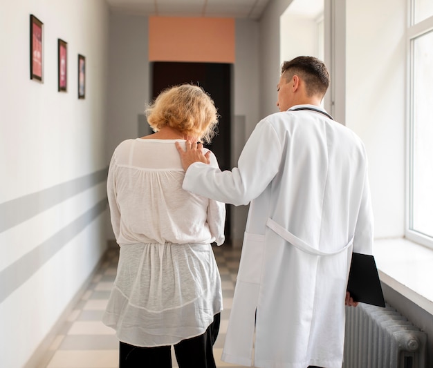 Foto grátis vista traseira paciente sênior e médico andando