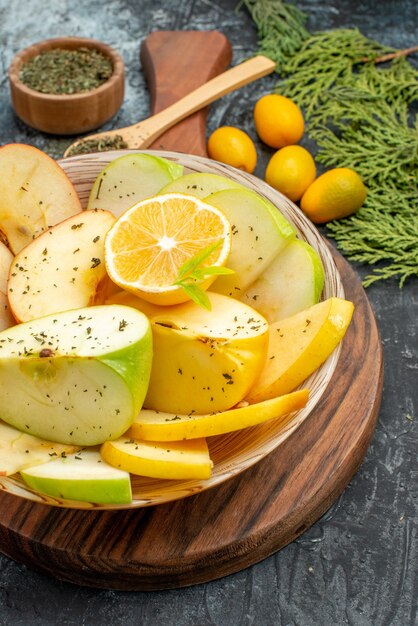 Vista vertical da coleção de frutas orgânicas frescas em um prato branco, talheres com limão e canela em um fundo escuro