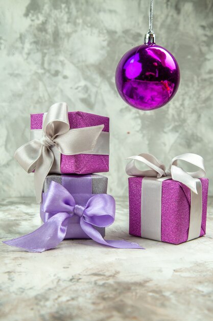 Vista vertical de três presentes de Natal para membros da família e um acessório de decoração em fundo de gelo