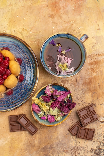 Vista vertical de uma xícara de bolo macio de chá quente de ervas com barras de chocolate de frutas e flores