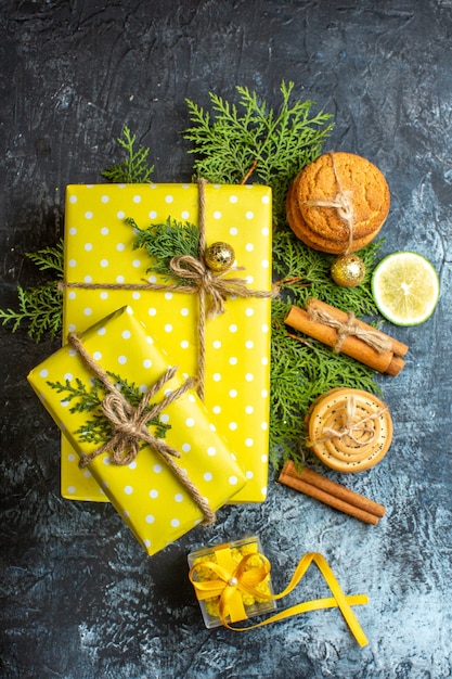 Vista vertical do plano de fundo do natal com lindas caixas de presente amarelas e biscoitos empilhados, limão e canela em fundo escuro