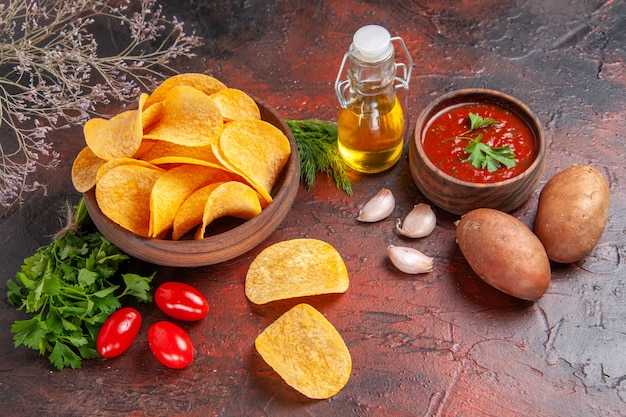 Visualização horizontal de deliciosas batatas fritas caseiras crocantes em uma pequena tigela marrom batata garrafa de óleo tomate verde alho e ketchup em fundo escuro