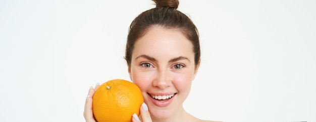 Foto grátis vitamina c e conceito de saúde jovem beleza segurando fruta laranja perto do conceito de rosto orgânico