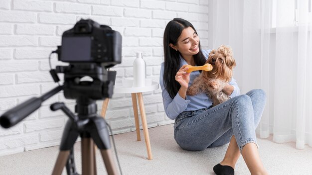 Vlogger feminina em casa com câmera e cachorro