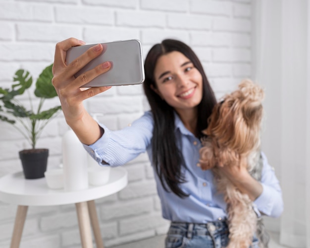 Foto grátis vlogger feminina em casa com smartphone e cachorro