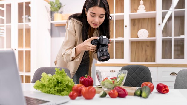 Vlogger feminina em casa tirando fotos com a câmera