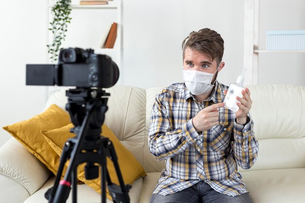 Vlogger gravando vídeo em casa com desinfetante para as mãos