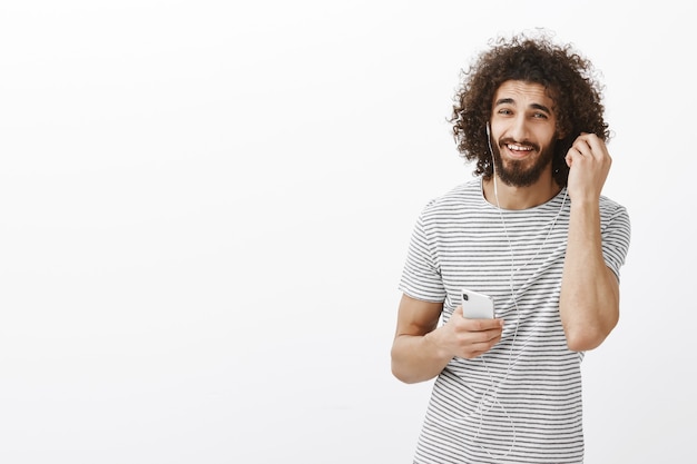 Você perguntou algo. Despreocupado e feliz cara oriental com camiseta listrada tirando os fones de ouvido e sorrindo