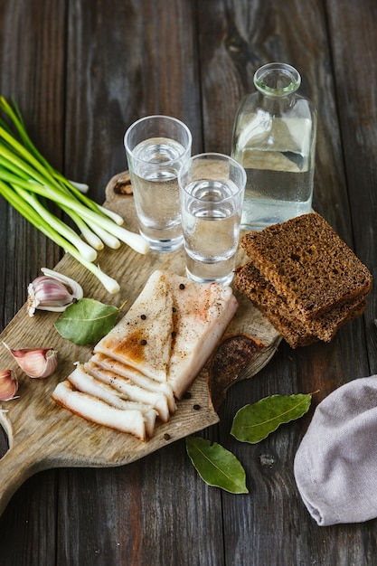 Vodka com banha e cebola verde na mesa de madeira