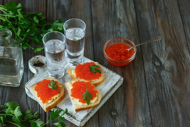 Vodka com caviar de salmão e torrada de pão na mesa de madeira