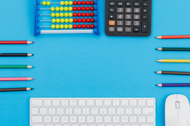 Foto grátis voltar ao conceito de escola com lápis, teclado, mouse, calculadora, ábaco na configuração plana de fundo azul.