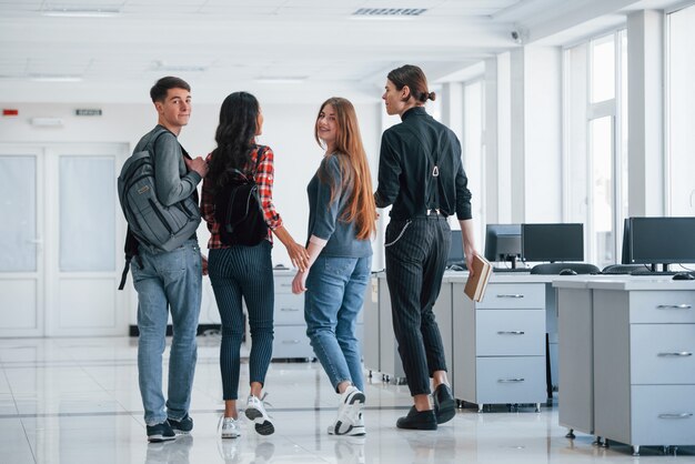 Voltar atrás. Grupo de jovens caminhando no escritório no intervalo