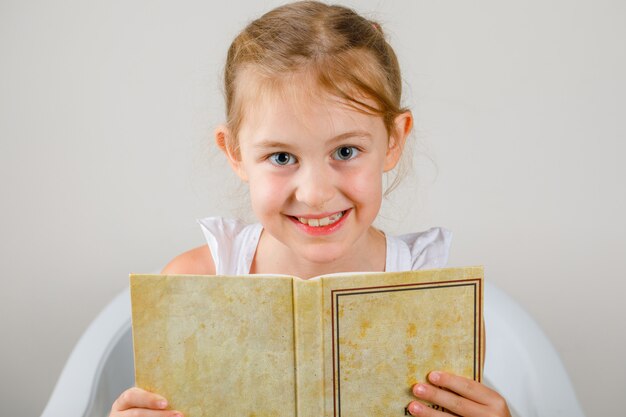 Voltar para a escola conceito vista lateral. menina sentada e segurando o livro.