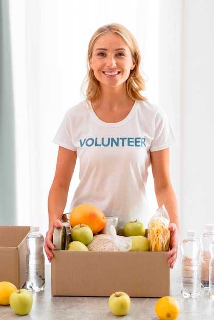 Voluntária alegre segurando uma caixa com comida para doação