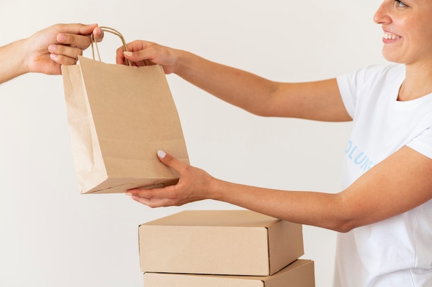 Voluntário sorridente entregando sacola de doações de alimentos