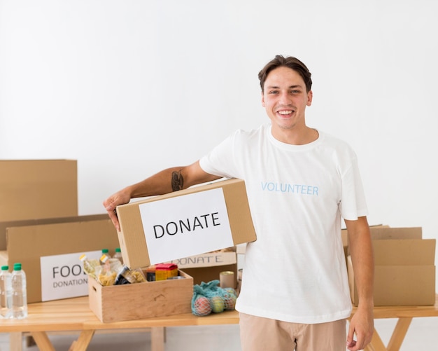 Voluntário sorridente segurando uma caixa de doações
