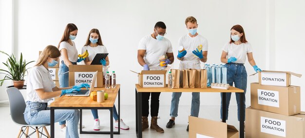 Voluntários com máscaras médicas e luvas preparando caixas para doação