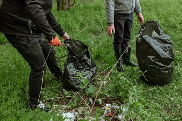 Voluntários com sacos de lixo em viagem à natureza, limpam o meio ambiente.