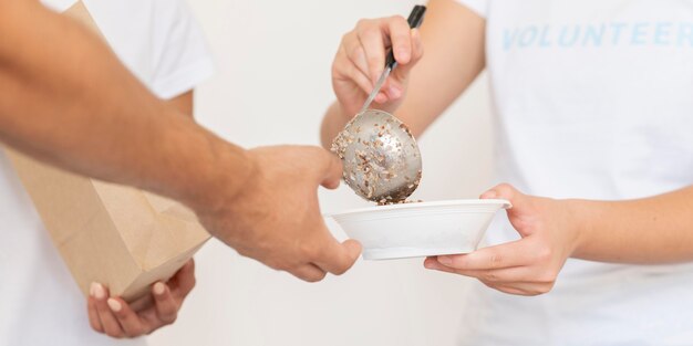 Voluntários entregando tigela de comida como doação