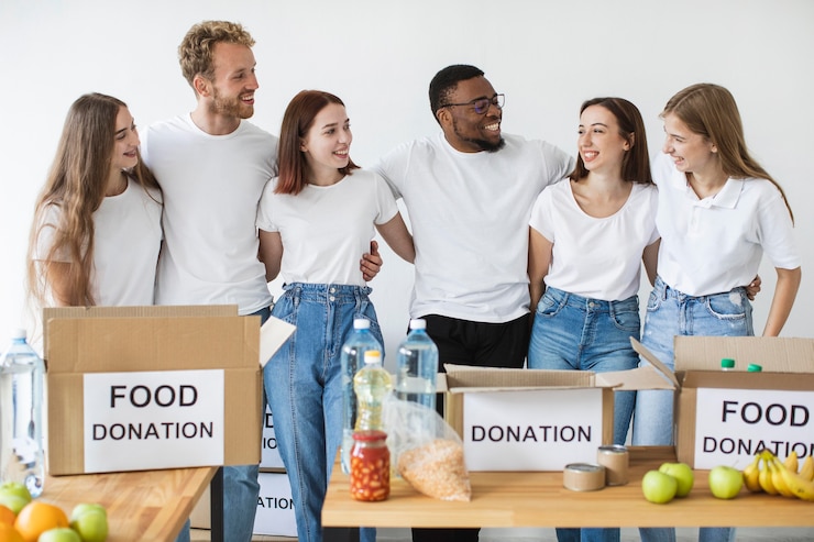 Foto grátis voluntários felizes se abraçando enquanto preparavam caixas de doações