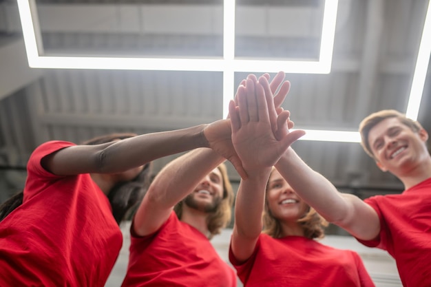 Voluntários. Jovens com camiseta vermelha parecendo alegres e felizes