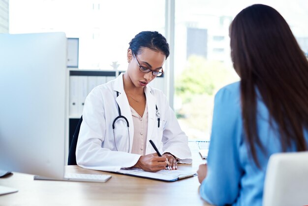 Vou escrever uma referência para você foto de uma jovem médica conversando com uma paciente em seu consultório