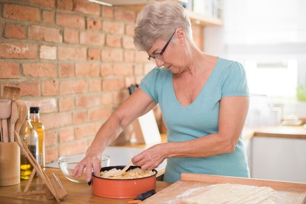 Vovó pensativa fazendo uma deliciosa torta de maçã