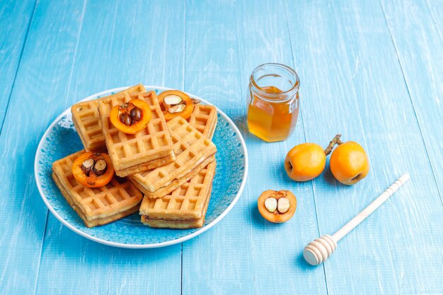 Waffles belgas quadrados com frutas de nêspera e mel.