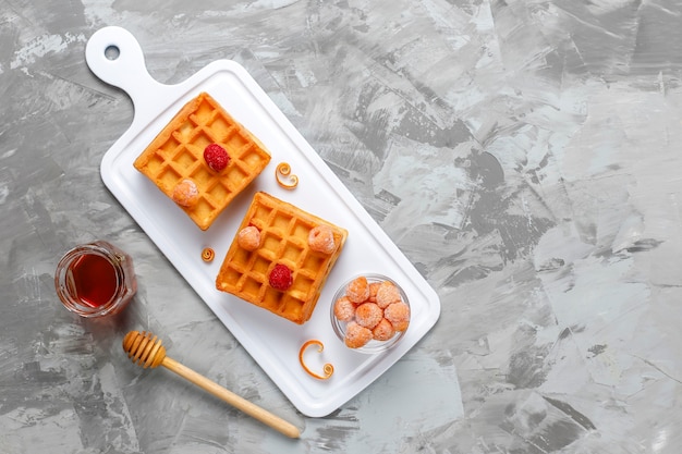 Waffles belgas tradicionais com mel e frutas congeladas.