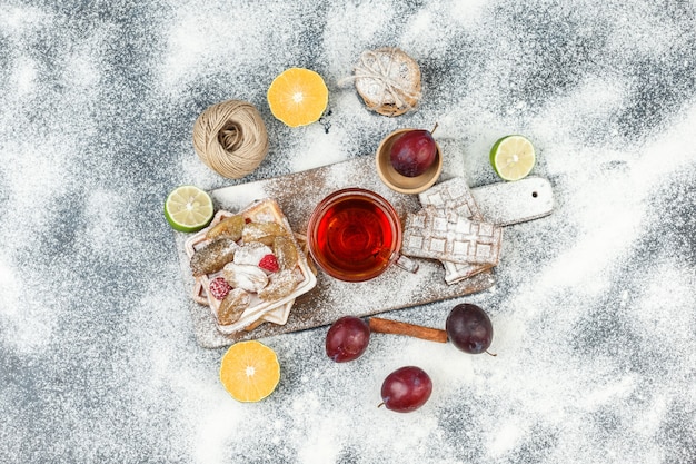 Waffles e bolachas de arroz com frutas cítricas, canela e biscoitos na superfície de mármore cinza escuro. horizontal