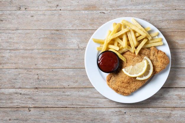 Foto grátis wiener schnitzel com batatas fritas na mesa wooedn