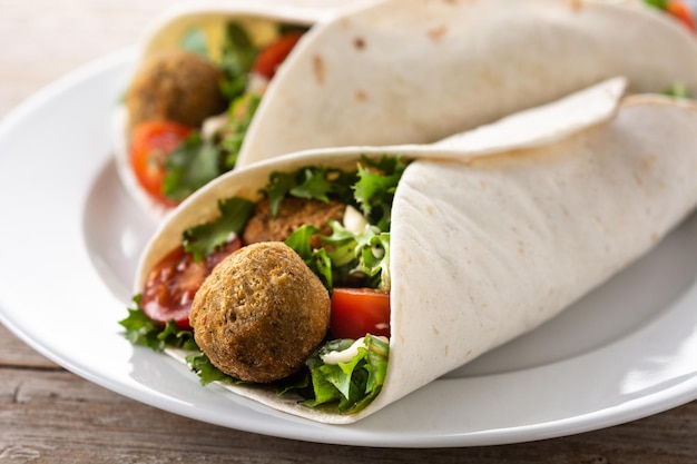 Wrap de tortilla com falafel e legumes na mesa de madeira