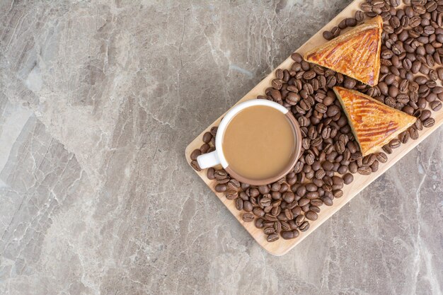 Xícara de café, biscoitos e grãos de café na placa de madeira. Foto de alta qualidade