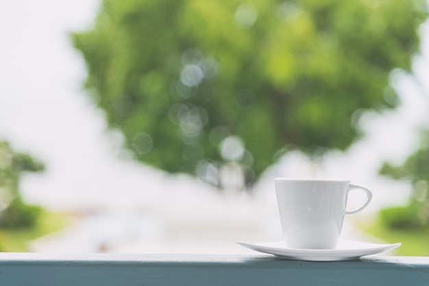 Xícara de café branca com fundo de vista ao ar livre - efeito de filtro vintage