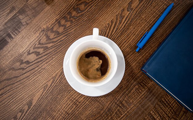 Xícara de café branca em um pires em uma mesa de madeira vista superior